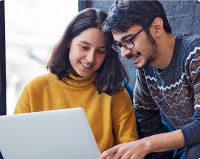 Two learners reviewing coursework on a laptop