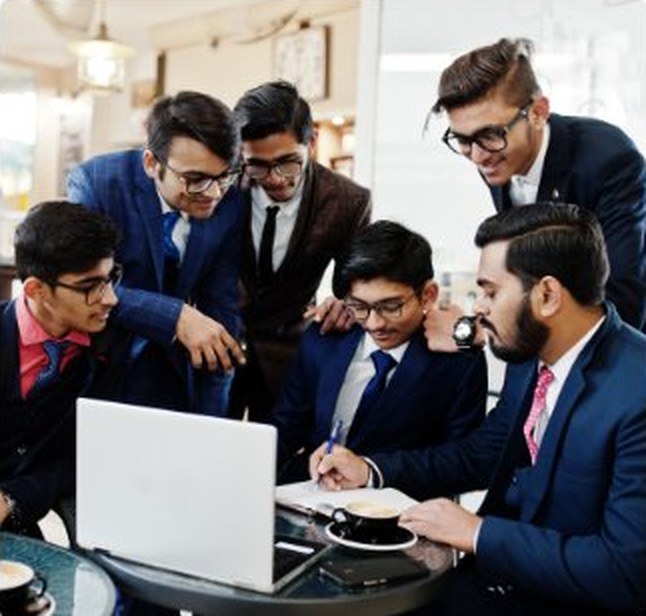Executive MBA learners discussing a project around a laptop